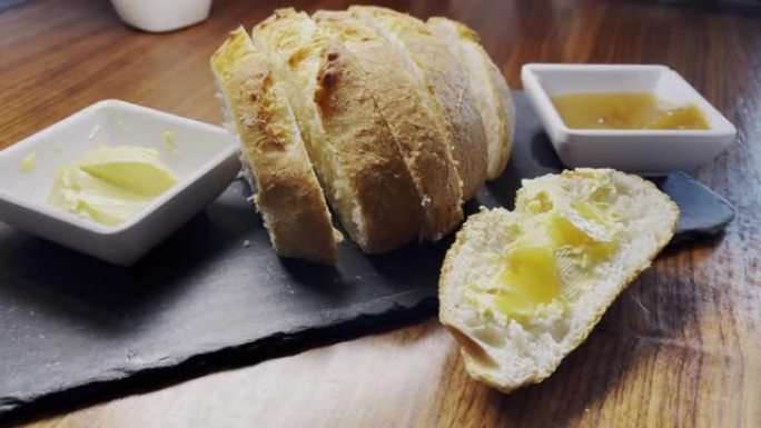 在奇瓦瓦市的一家小咖啡馆里，将一块新鲜出炉的面包放在石板拼盘上，上面放着黄油和苹果果酱，上面放着黄油