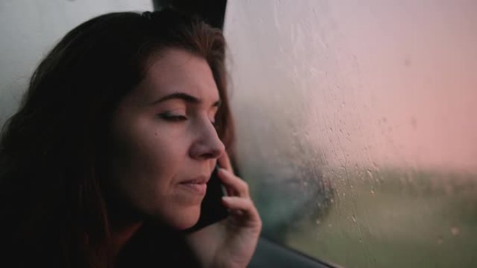 年轻女子在外面下雨时在车内打电话。