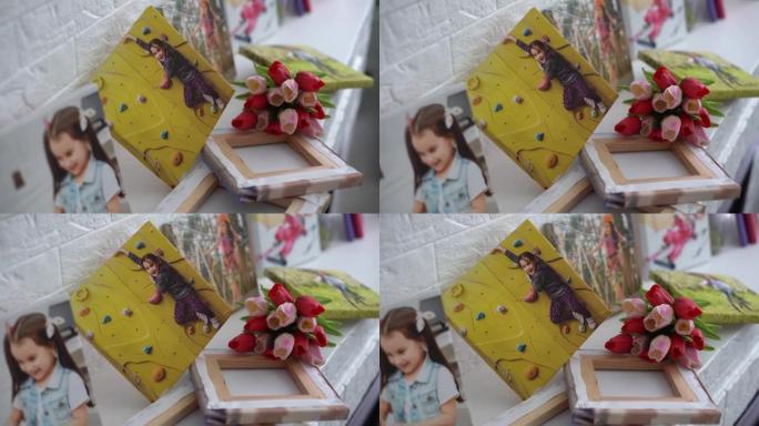 活跃的小女孩和鲜花郁金香的照片画布作为节日礼物躺在架子上