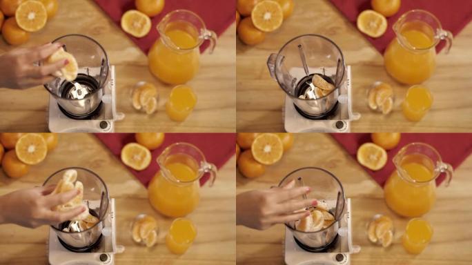 女性的手将新鲜的橙片加入搅拌机研磨机中制成果汁