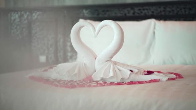 两只天鹅毛巾在床上看起来像心形