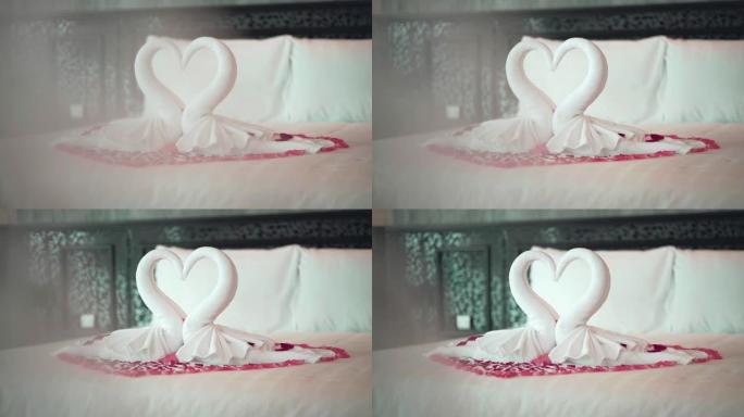 两只天鹅毛巾在床上看起来像心形