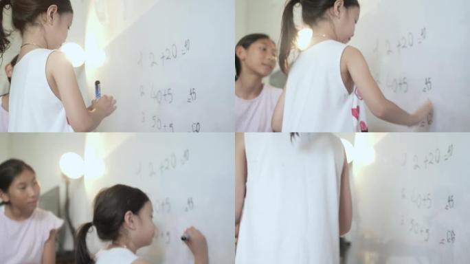 快乐的亚洲女孩用白板为姐姐教数学，女孩在家锻炼，新型冠状病毒肺炎在家上学。