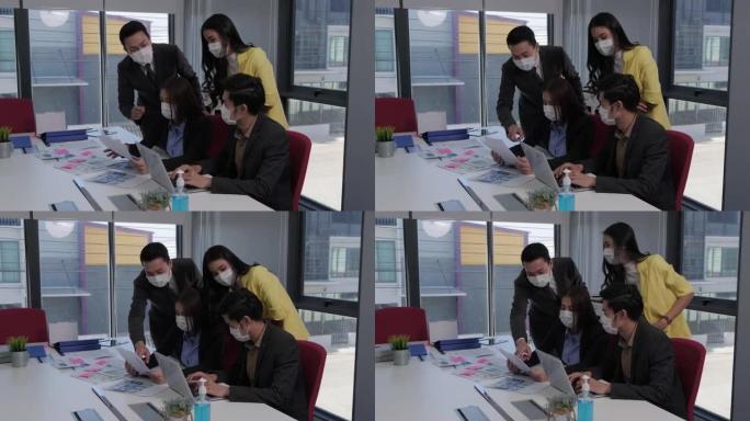 一名亚裔女员工正在向上司寻求工作计划方面的建议。团队中的每个人都戴着口罩，以防止新型冠状病毒肺炎病毒