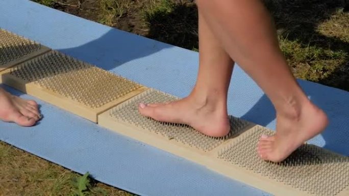 在瑜伽节上，女人的脚赤脚在木板上走路，指甲锋利