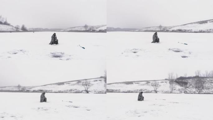 带着钓鱼竿的渔夫正坐在冰冻池塘的冰洞附近。人在冬季钓鱼时抓鱼，空中无人机视图。