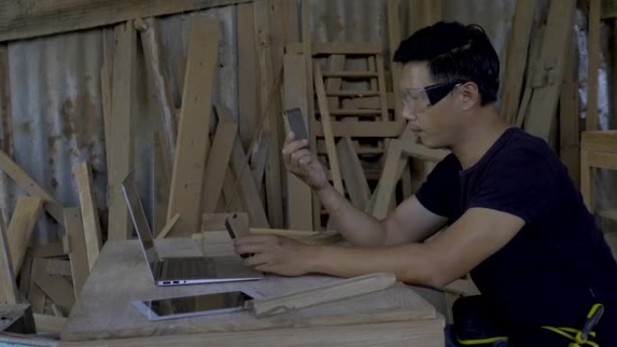 男人是手握平板电脑的熟练木匠，在网上卖木家具，在网站上卖东西