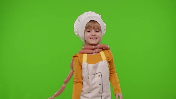 作为厨师厨师的儿童女孩孩子呆在香肠上，鬼混，做鬼脸，竖起大拇指