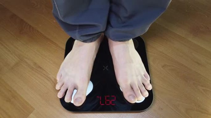 男人检查他的体重。秤上的腿。