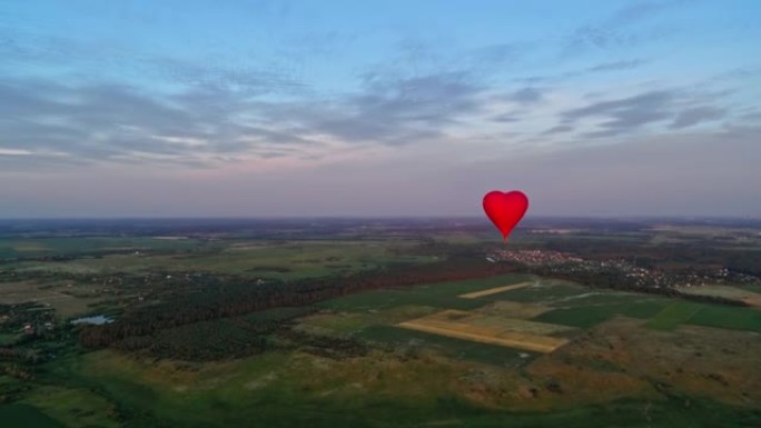 恋爱心形的红色气球。自然景观和美丽热气球的全景。明亮的浮空器在田野上空飞行。