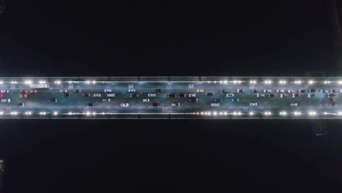 夜间交通在河上架桥。夜间驾驶汽车，前灯反射的道路俯视图