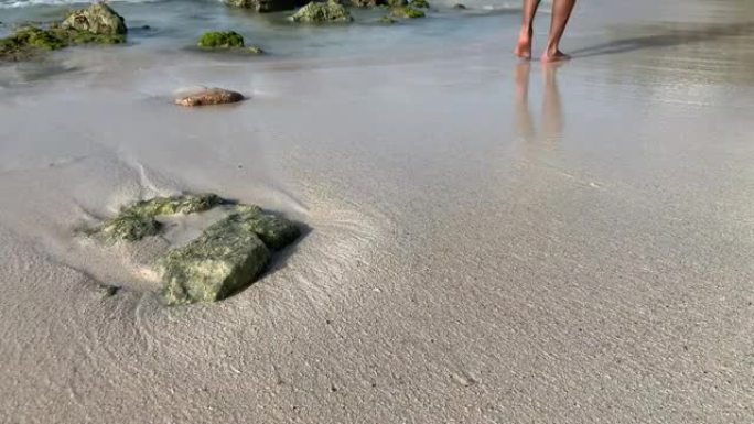当加勒比海海浪撞击裸露的岩石时，男性壮举将水溅到潮湿的沙滩上。
