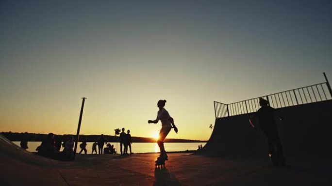 剪影轮滑在轮滑公园，两个少年在日落的背景下进行复杂的跳跃