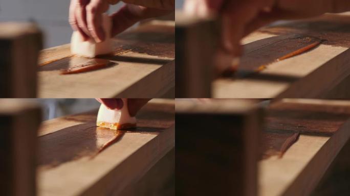 木工将木材浸渍剂应用于木材产品。一名男子用木油盖住木架