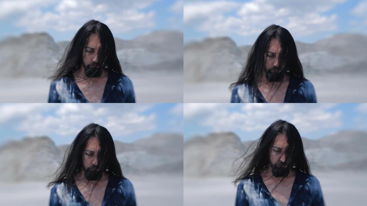 沙漠中孤独疲惫的旅行者的肖像。长发男人，穿着脏衣服，面对蓝天，头发飘动。镜头婴儿拍摄慢动作200 f