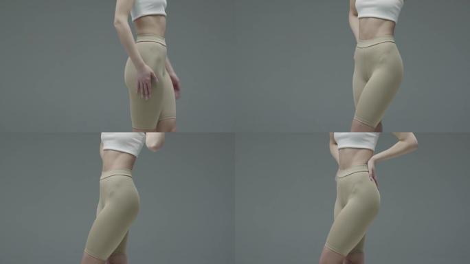 在灰色背景下，女性健康和脂肪团概念上，让女性臀部和臀部穿着纯粹的运动舒适运动服