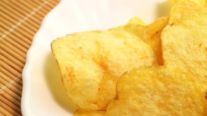 自制薯片。快餐。受欢迎的垃圾食品。马铃薯块茎和薯片在竹餐巾上平稳旋转。糖尿病饮食。