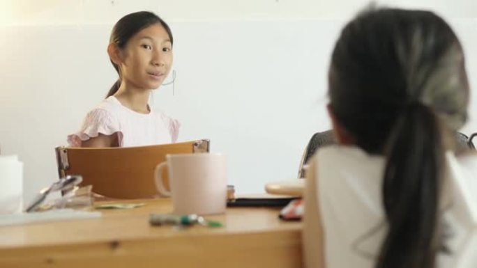 亚洲女孩在新型冠状病毒肺炎期间在家为姐姐在白板上教数学，社交距离概念。