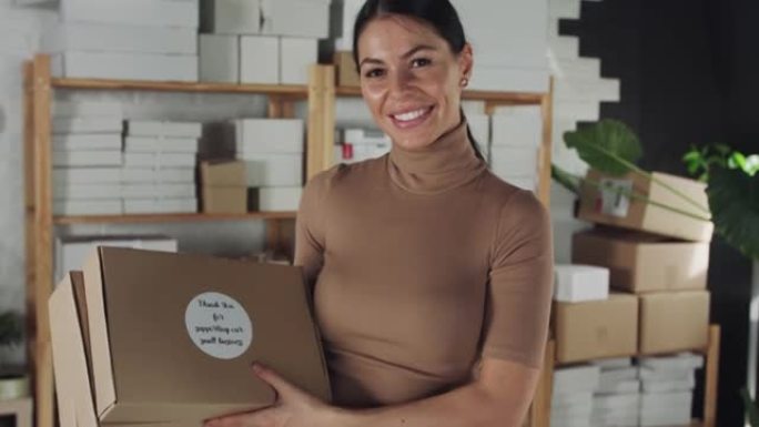 年轻的女企业家拿着 “谢谢” 包裹，对着镜头微笑