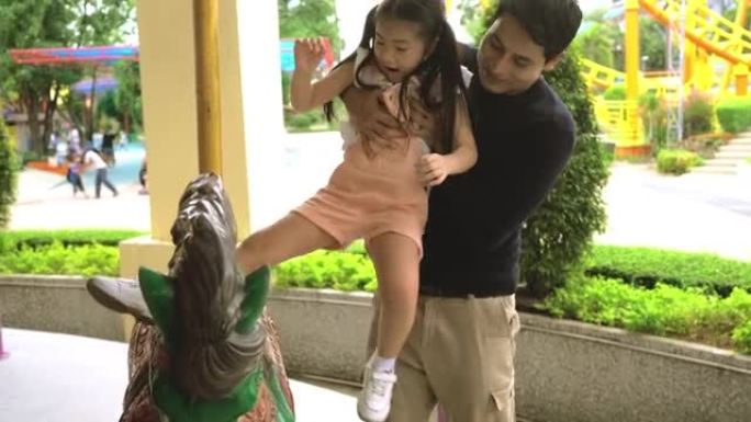 亚洲爸爸和他的女儿玩旋转木马。