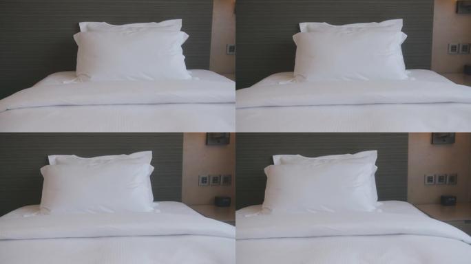 多莉拍摄的4k镜头美丽休闲白色柔软枕头和床单卧室舒适放松室内设计家居室内细节概念