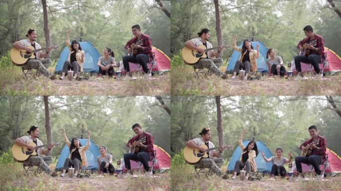 徒步旅行和露营概念。四名亚洲男女在树林里露营，唱歌和弹吉他很有趣。