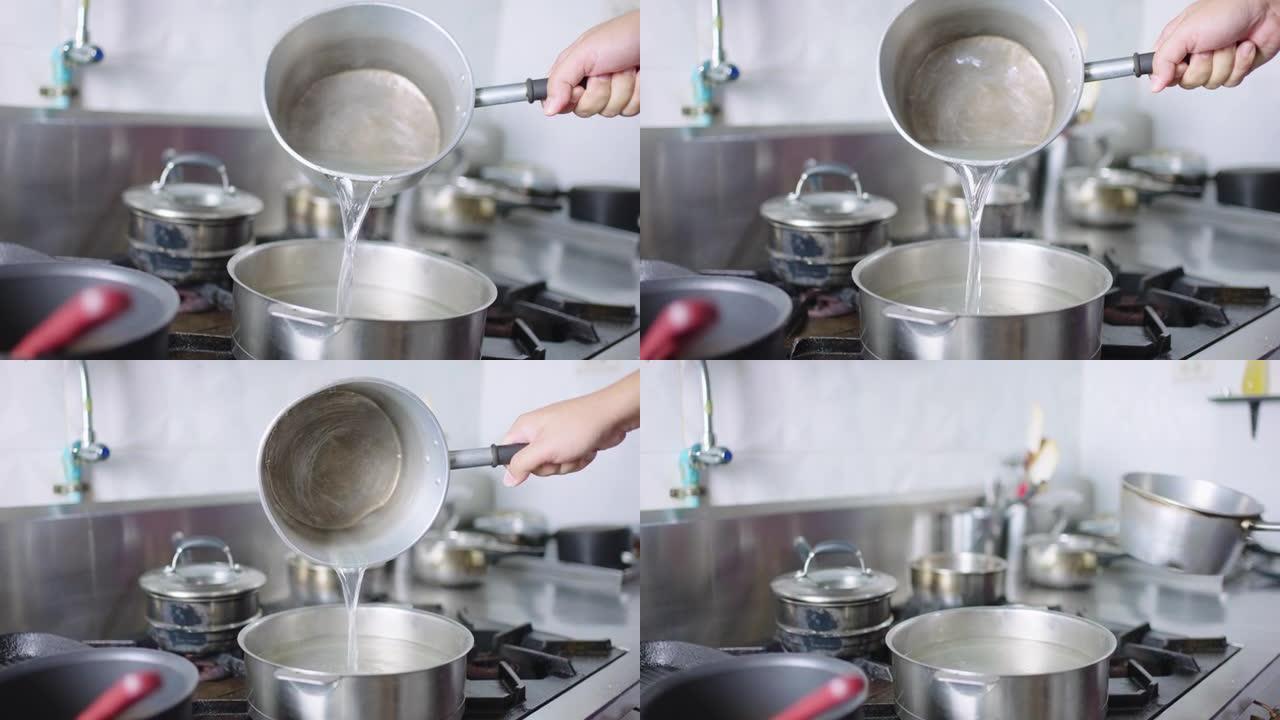 SLO MO: 厨师的手将热水倒入锅中。