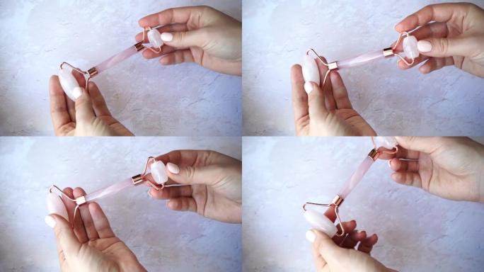 刮痧按摩器玉辊在女性手中。粉红玉石用于面部和身体护理