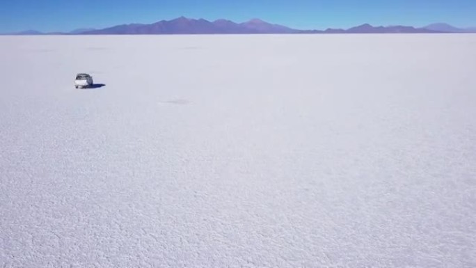 汽车在乌尤尼盐滩上行驶。著名的玻利维亚乌尤尼盐滩的鸟瞰图，汽车在其表面上移动