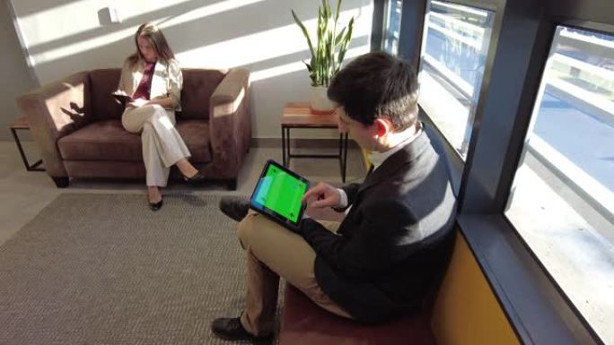 高角度多莉在两个商务人士在商务等候室等待平板电脑上浏览
