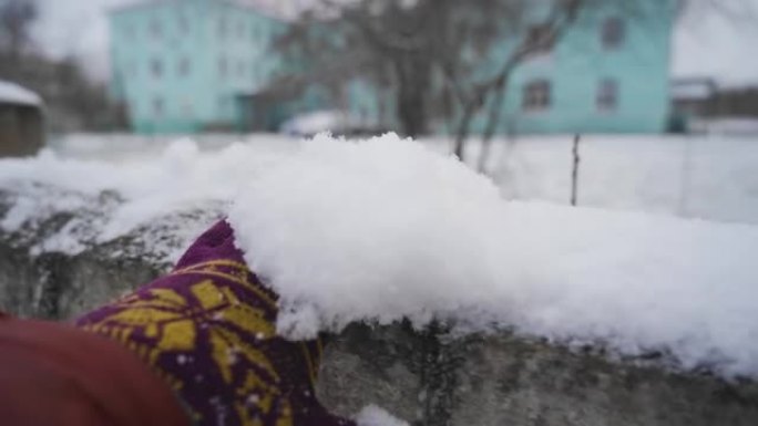 一个人戴着手套在篱笆上移动雪。玩雪。手的慢动作镜头。