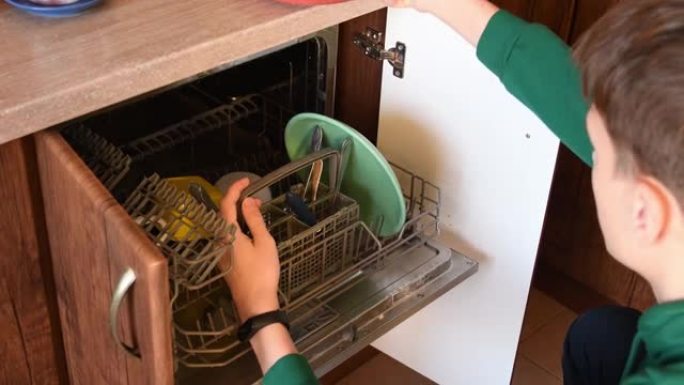 年轻人从洗碗机里拿干净的餐具盘子。做家务的人