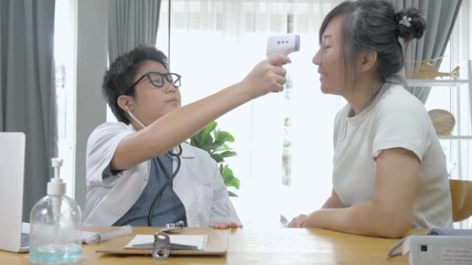 亚洲医生男孩使用红外温度计与病人在家里，锁定生活方式的概念。