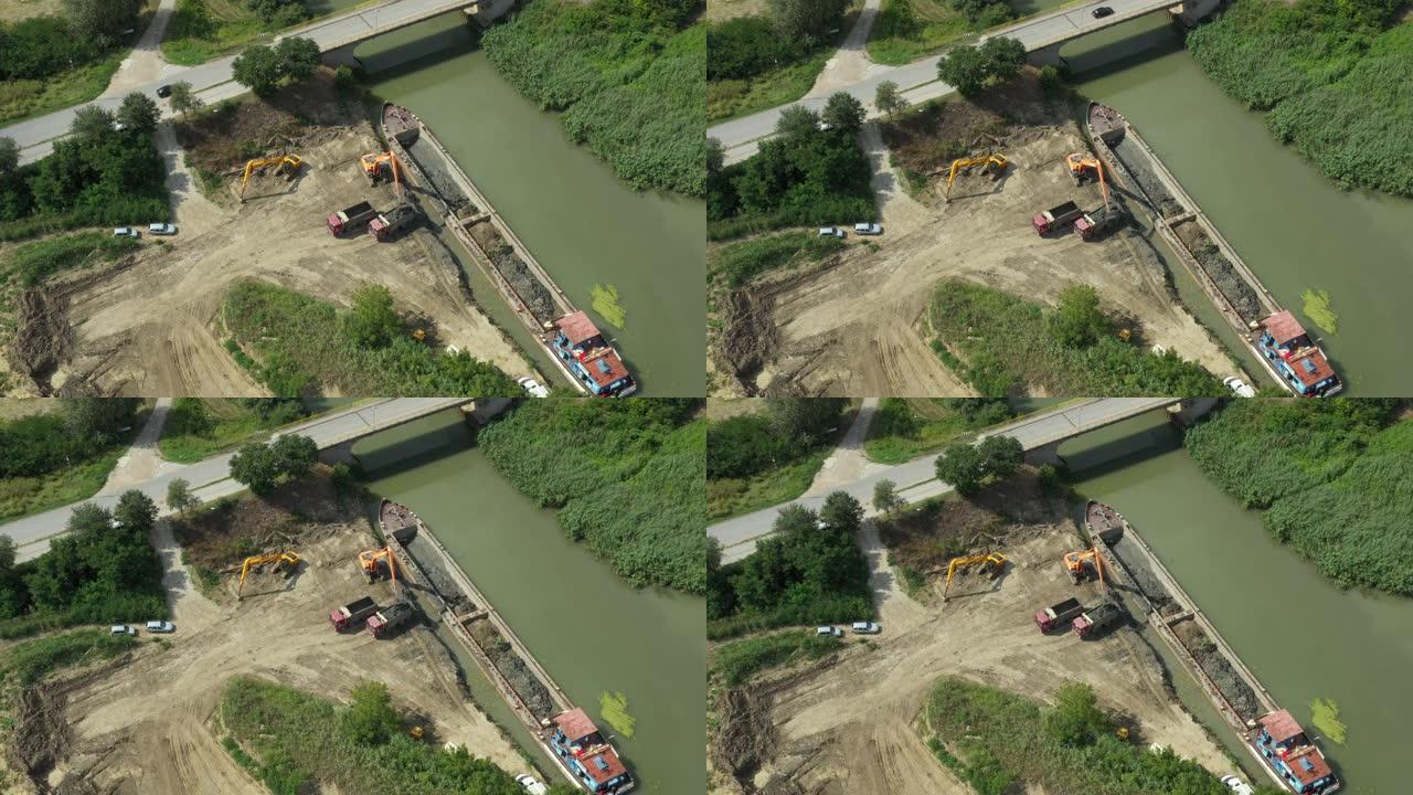 挖掘机将挖泥机从驳船重新装载到自卸车中的鸟瞰图