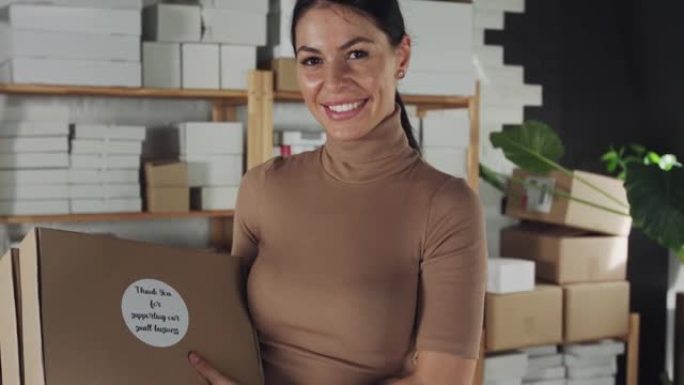 快乐女企业家拿着包裹对着镜头微笑