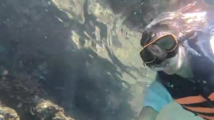 亚洲游客潜水的机芯动作相机在水下观看大自然的美丽，泰国，甲米府，皮皮岛