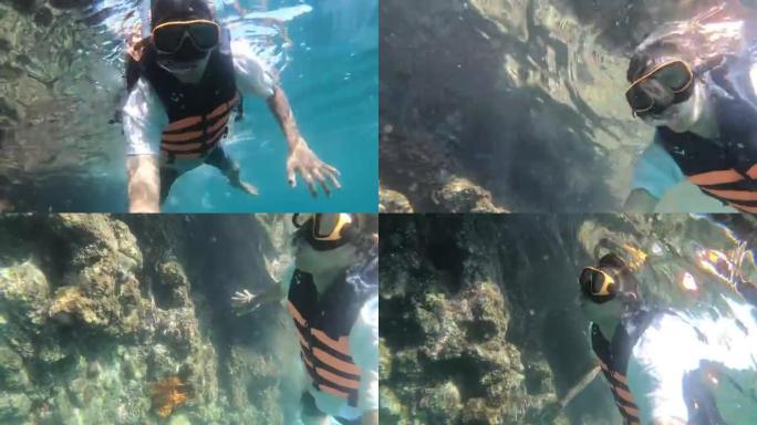 亚洲游客潜水的机芯动作相机在水下观看大自然的美丽，泰国，甲米府，皮皮岛