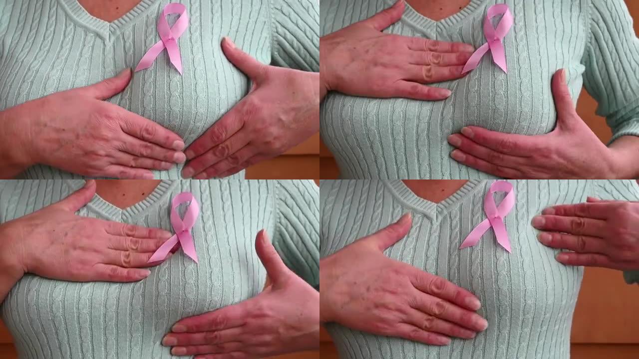 一个成熟女人的手在检查她的乳房。粉红色的徽章丝带系在蓝色或薄荷色的针织毛衣上。预防乳腺癌的概念