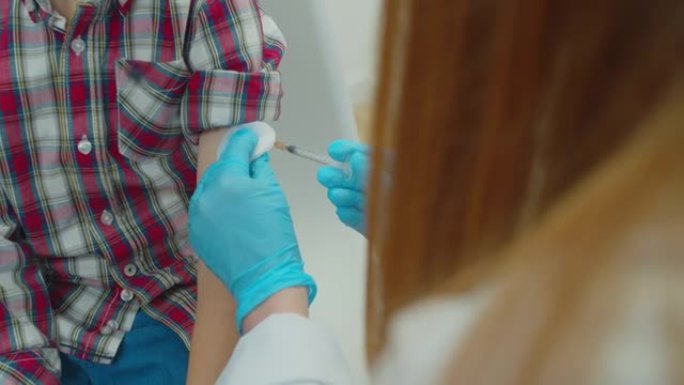 冠状病毒期间，小病人坐在家里戴口罩，而专业医生手给孩子注射疫苗。疫苗接种概念。