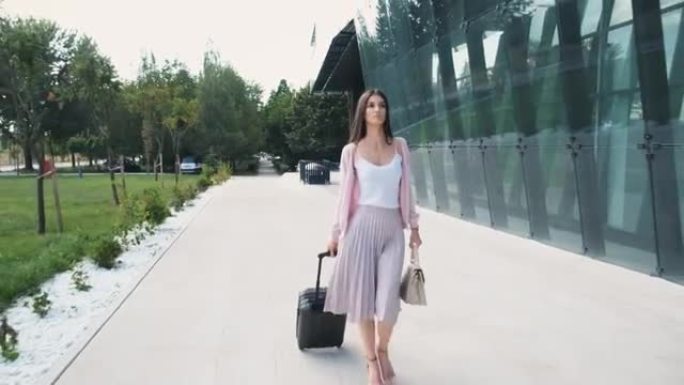 一位美丽的女商人在城市中行走并拉着手提箱