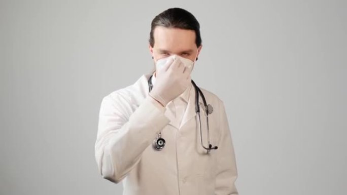 一位穿着睡袍和衬衫的年轻男医生戴上医用口罩。