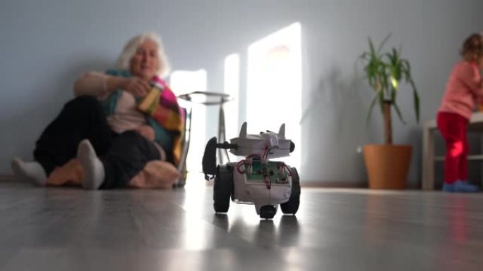 奶奶在看的时候，蹒跚学步的女孩在客厅玩玩具机器人的视频