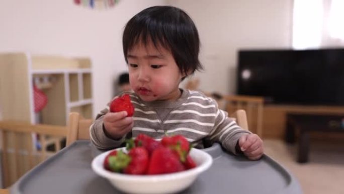 在餐厅吃草莓的小男孩