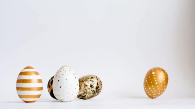 鸡蛋在白色的桌子上滚动，互相敲打。复活节金色装饰的鸡蛋孤立在白色背景上。最小的复活节概念。复活节快乐