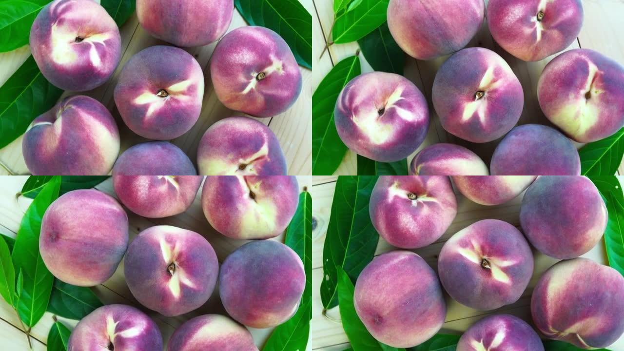 俯视图旋转新鲜桃子与叶子特写，桃子水果在花园的木桌上。
