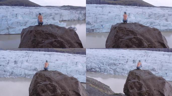 女人的无人机蹲在冰川上的岩石上