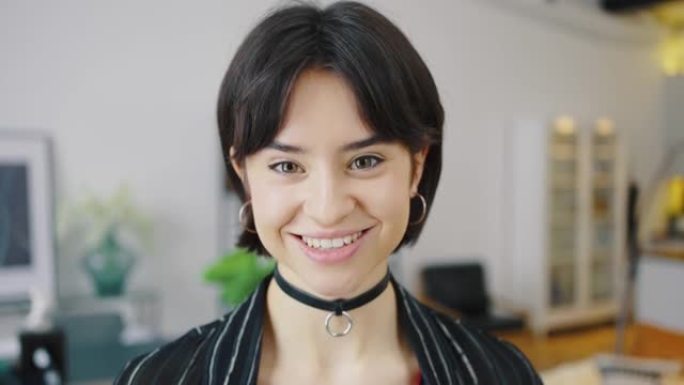 穿着休闲服微笑的年轻黑发女女孩，在舒适的家庭背景下摆姿势。人们情感生活方式概念。富有表现力的绿色眼睛