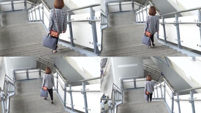 年轻的亚洲妇女从空中火车平台上走下楼梯