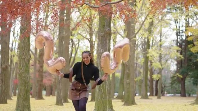 年轻的非裔美国妇女拿着25个数字气球快乐地跳舞