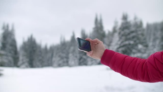 英俊的男人独自旅行者在山上拍照，同时思考冬天白雪覆盖的松树森林的美丽。在新型冠状病毒肺炎大流行的同时